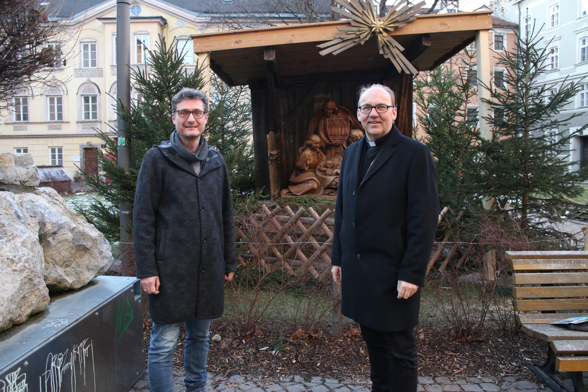 Zwei Männer vor religiösem Denkmal im Wald in Innsbruck