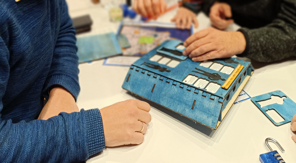 Eine blaue Holz-Kiste mit Rätseln und Zahlenschlösser.