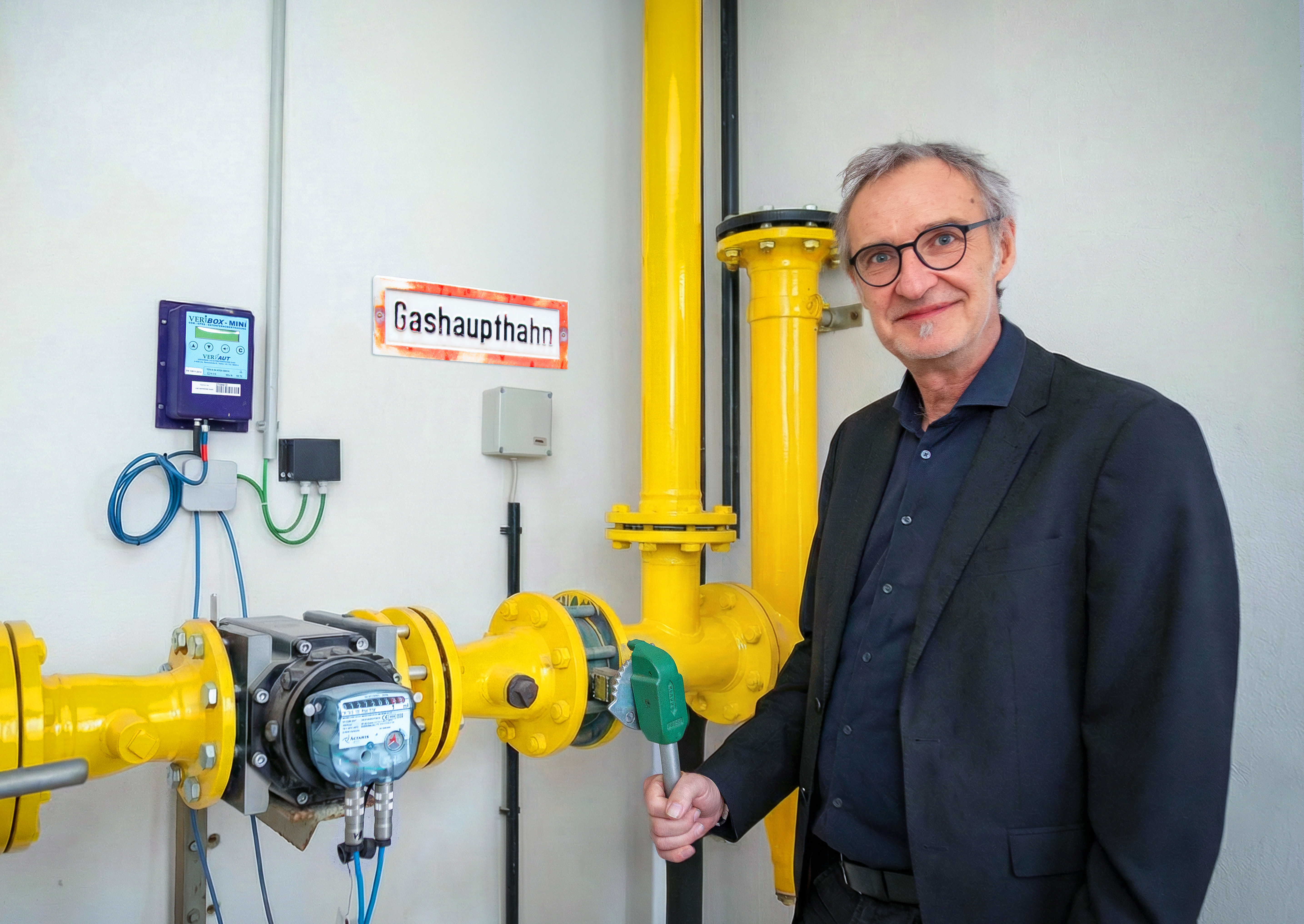 Mann mittleren Alters steht vor dem Gashaupthahn und dreht an einem Henkel
