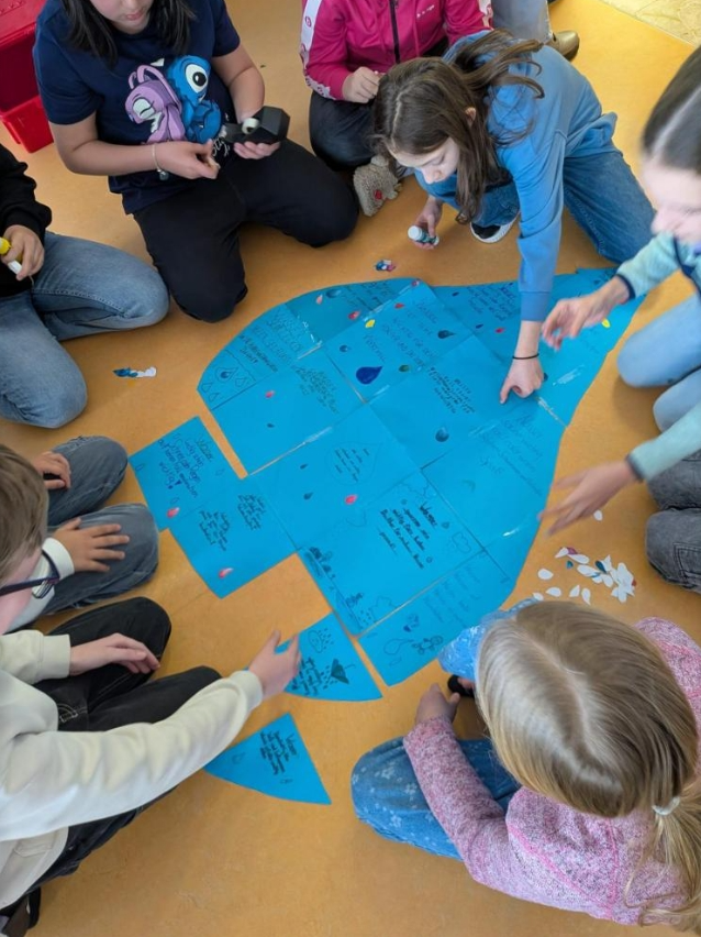 Schüler:innen sitzen am Boden und arbeiten mit blauen Zetteln